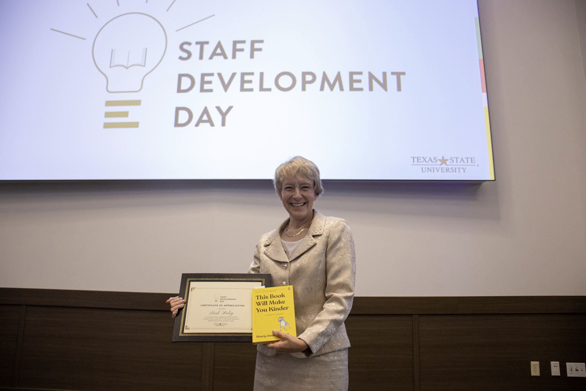 lark doley holding a book and a certificate